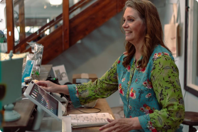 A woman happily using Clover Flex to accept a payment in her store