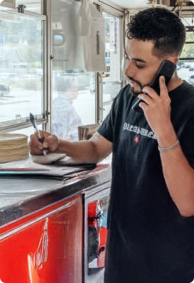A man in a food truck on the phone taking orders