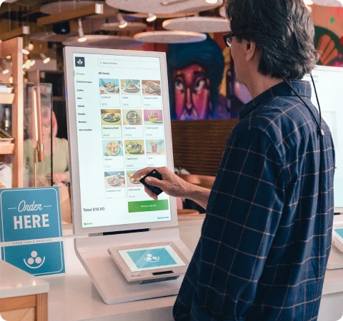 A person using a Clover Kiosk to order food from a restaurant