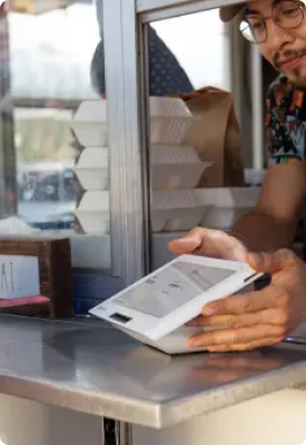 A man using  Clover Mini to take a transaction from a drive-thru window