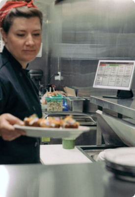 A a woman serving a dish in a restaurant and using Clover Solo